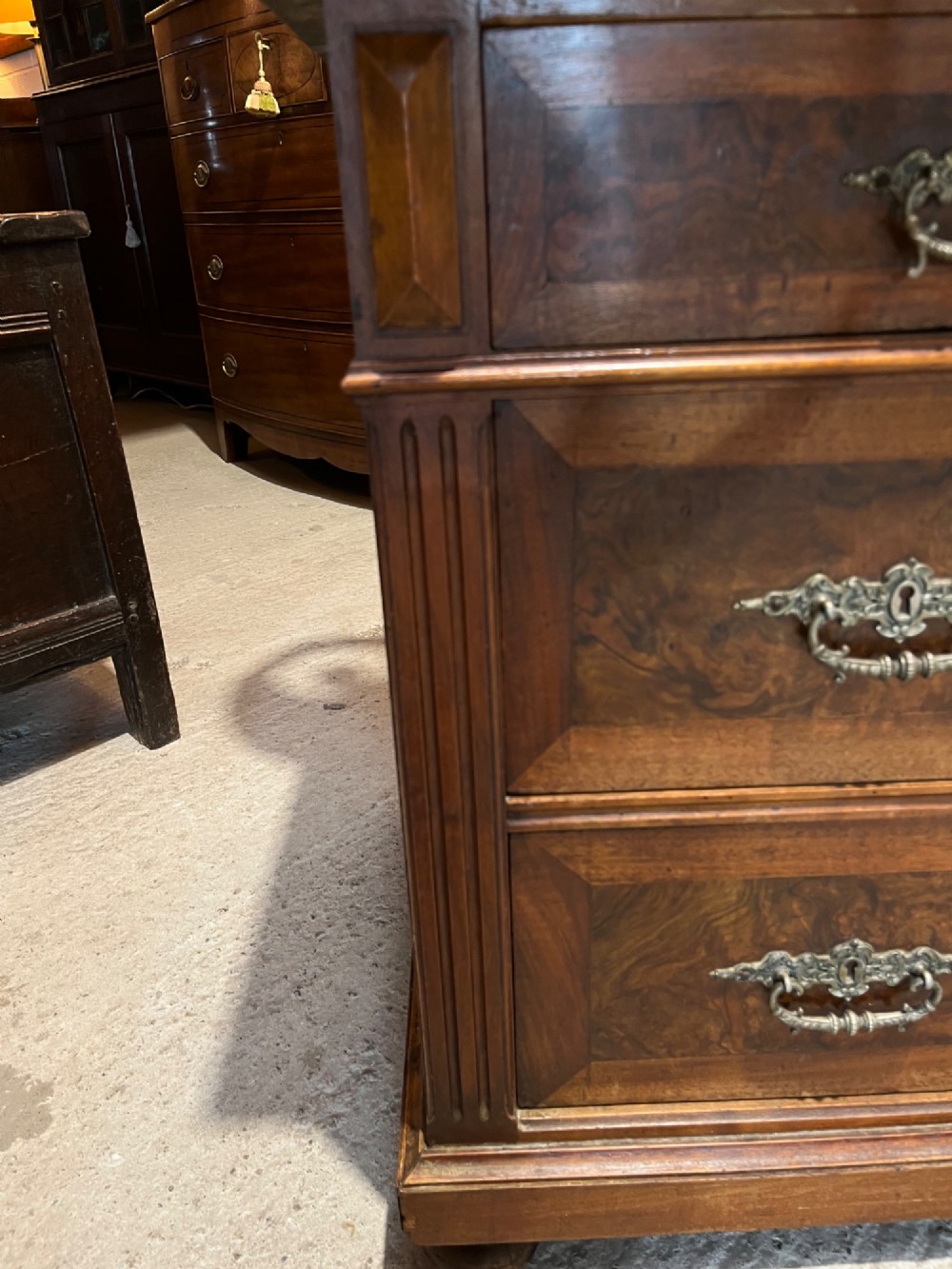 An antique 19th-century French walnut chest of drawers featuring a dark grey marble top and ornate brass handles. View XI