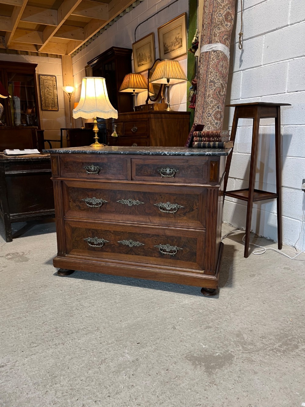 An antique 19th-century French walnut chest of drawers featuring a dark grey marble top and ornate brass handles. View XII