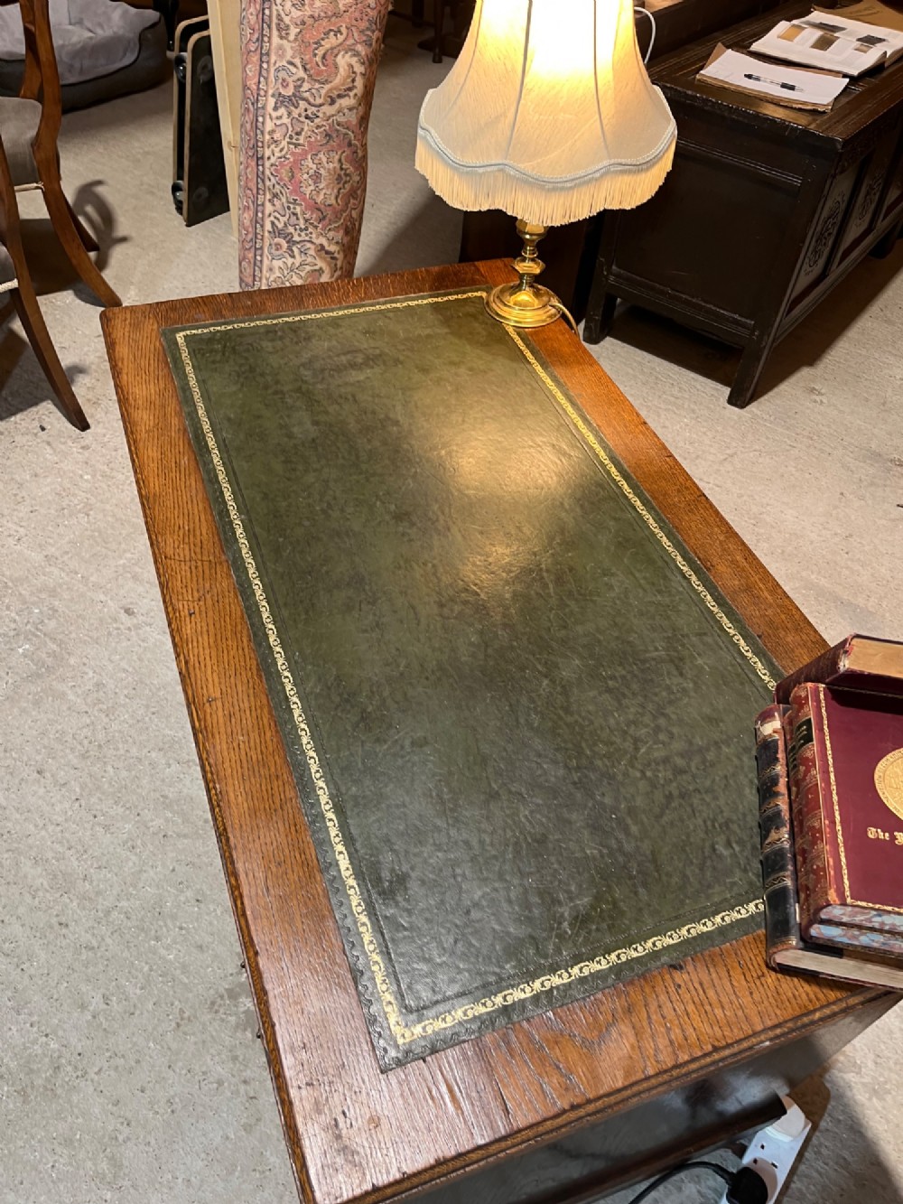 A late nineteenth-century dark oak pedestal desk featuring nine drawers with brass swan-neck handles and a green leather inset writing surface. View VI