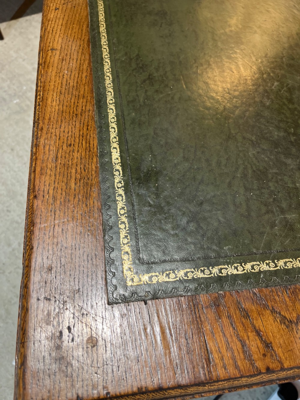 A late nineteenth-century dark oak pedestal desk featuring nine drawers with brass swan-neck handles and a green leather inset writing surface. View VII