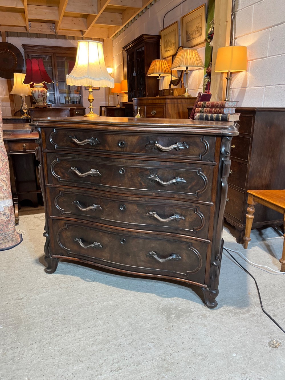 A nineteenth-century French dark mahogany chest of drawers featuring a serpentine front, four drawers with brass handles, and moulded panel detailing. View II