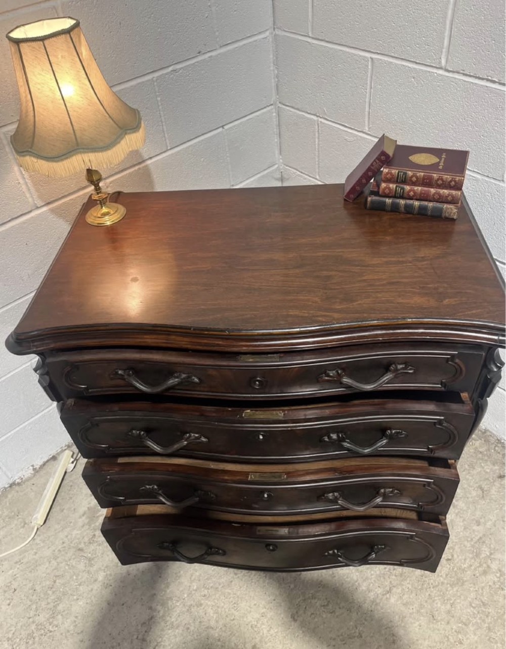 A nineteenth-century French dark mahogany chest of drawers featuring a serpentine front, four drawers with brass handles, and moulded panel detailing. View V