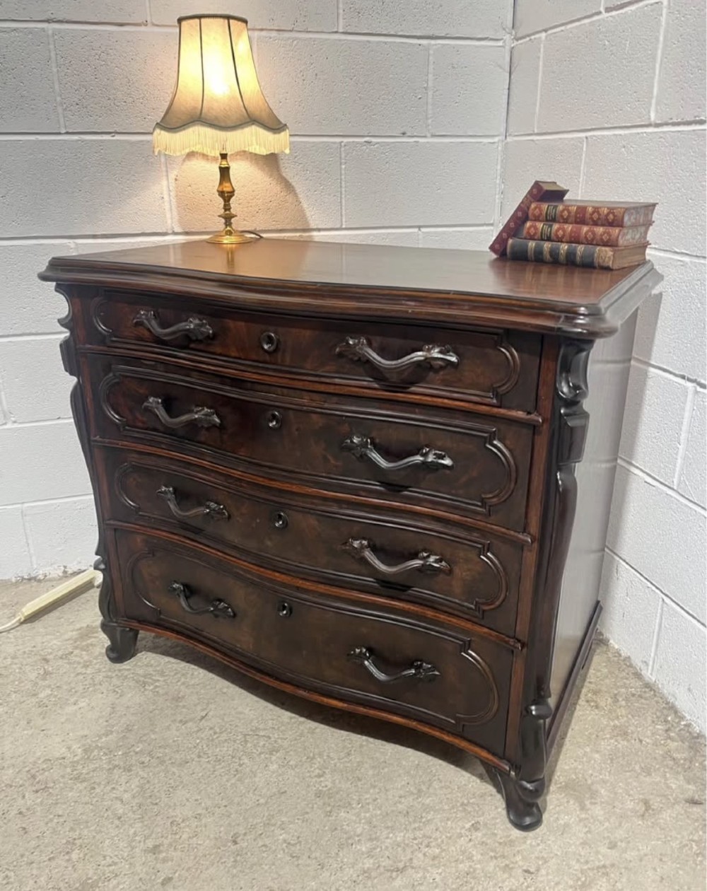 A nineteenth-century French dark mahogany chest of drawers featuring a serpentine front, four drawers with brass handles, and moulded panel detailing. View VI