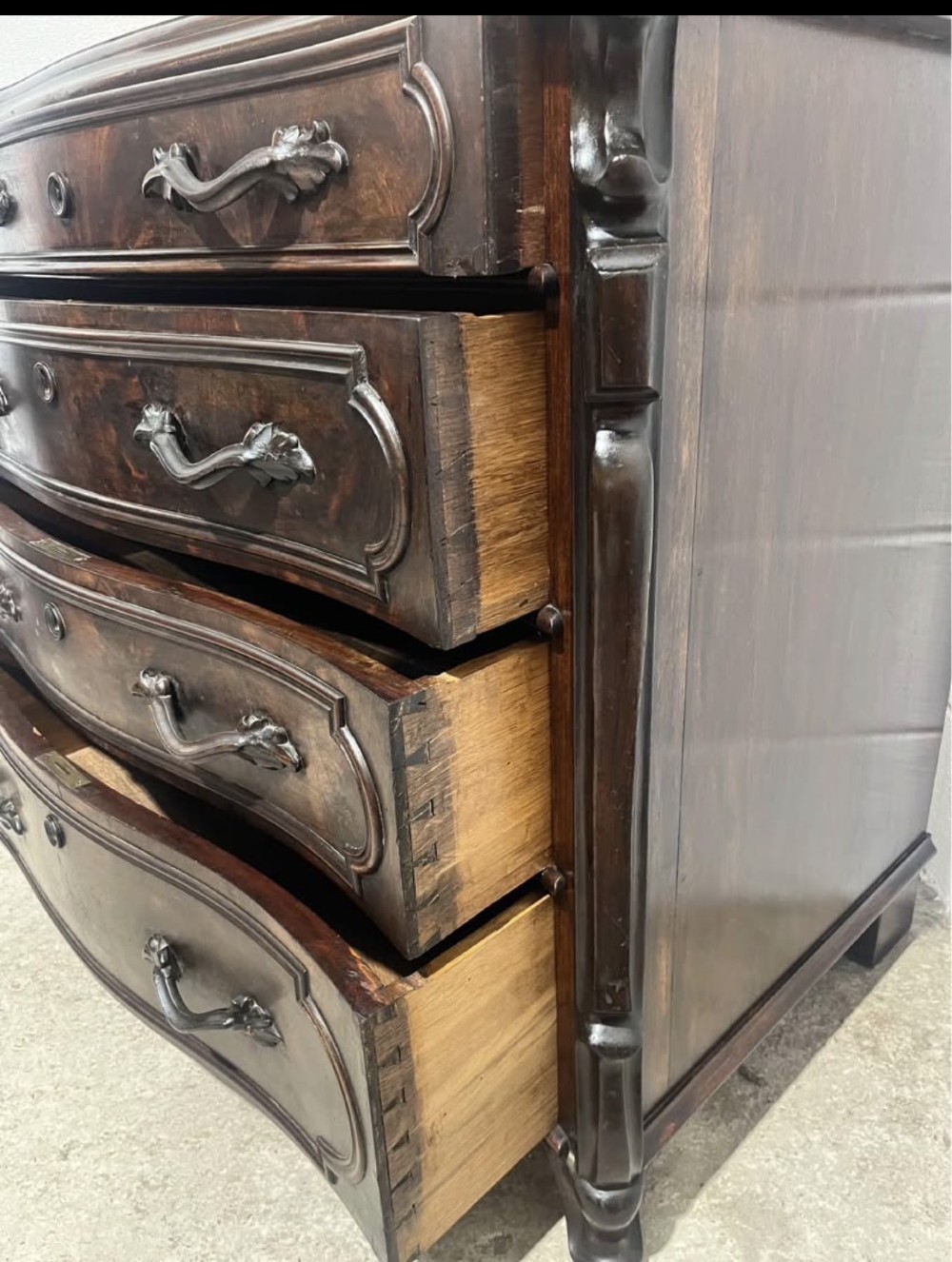 A nineteenth-century French dark mahogany chest of drawers featuring a serpentine front, four drawers with brass handles, and moulded panel detailing. View VII