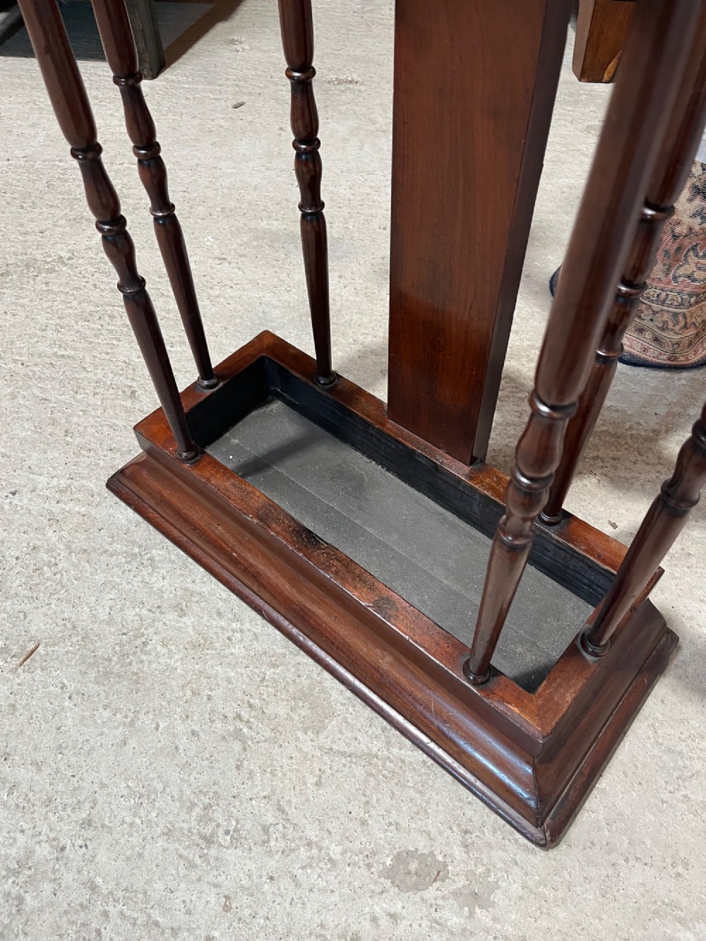 A 19th-century mahogany freestanding hall stand featuring turned wooden pegs on curved scroll arms above a lower umbrella holder with a drip tray. View VIII