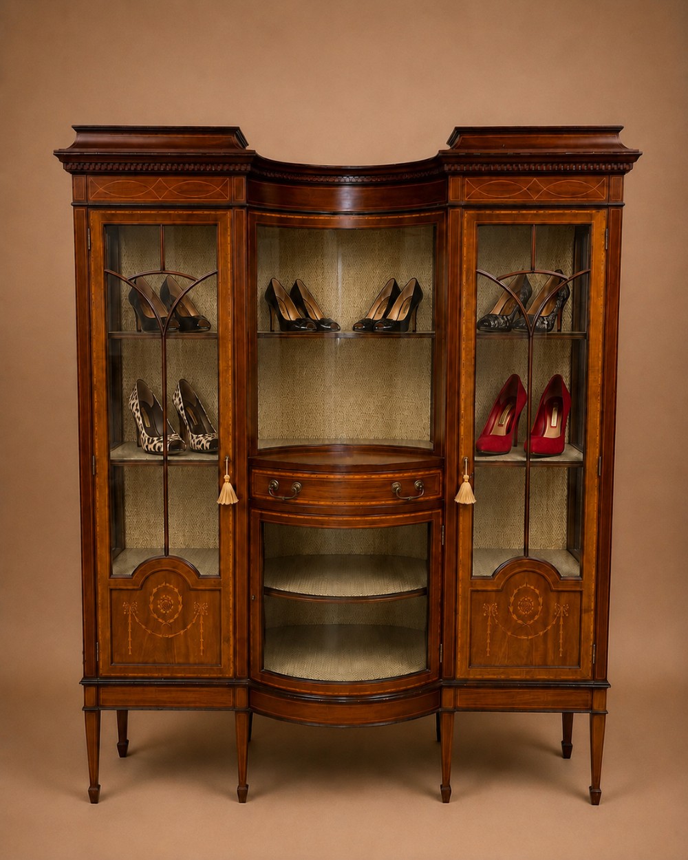 A late 19th-century inlaid mahogany display cabinet featuring glazed doors with astragal glazing, a concave centre section, satinwood marquetry swags, and slender square tapered legs. View II