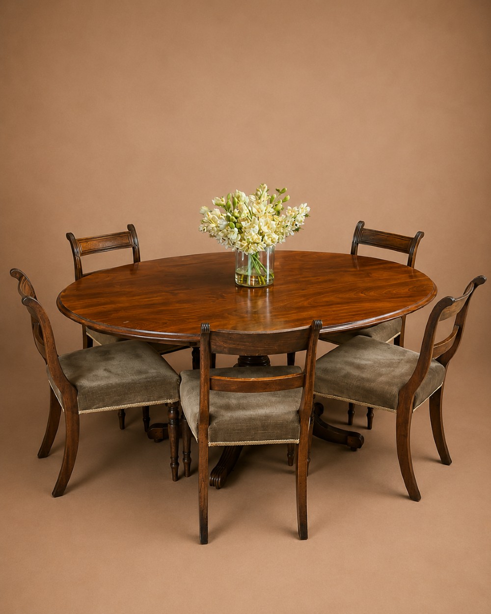 An oval Regency mahogany dining table featuring a central turned pedestal supported by four reeded sabre legs with brass casters. View II