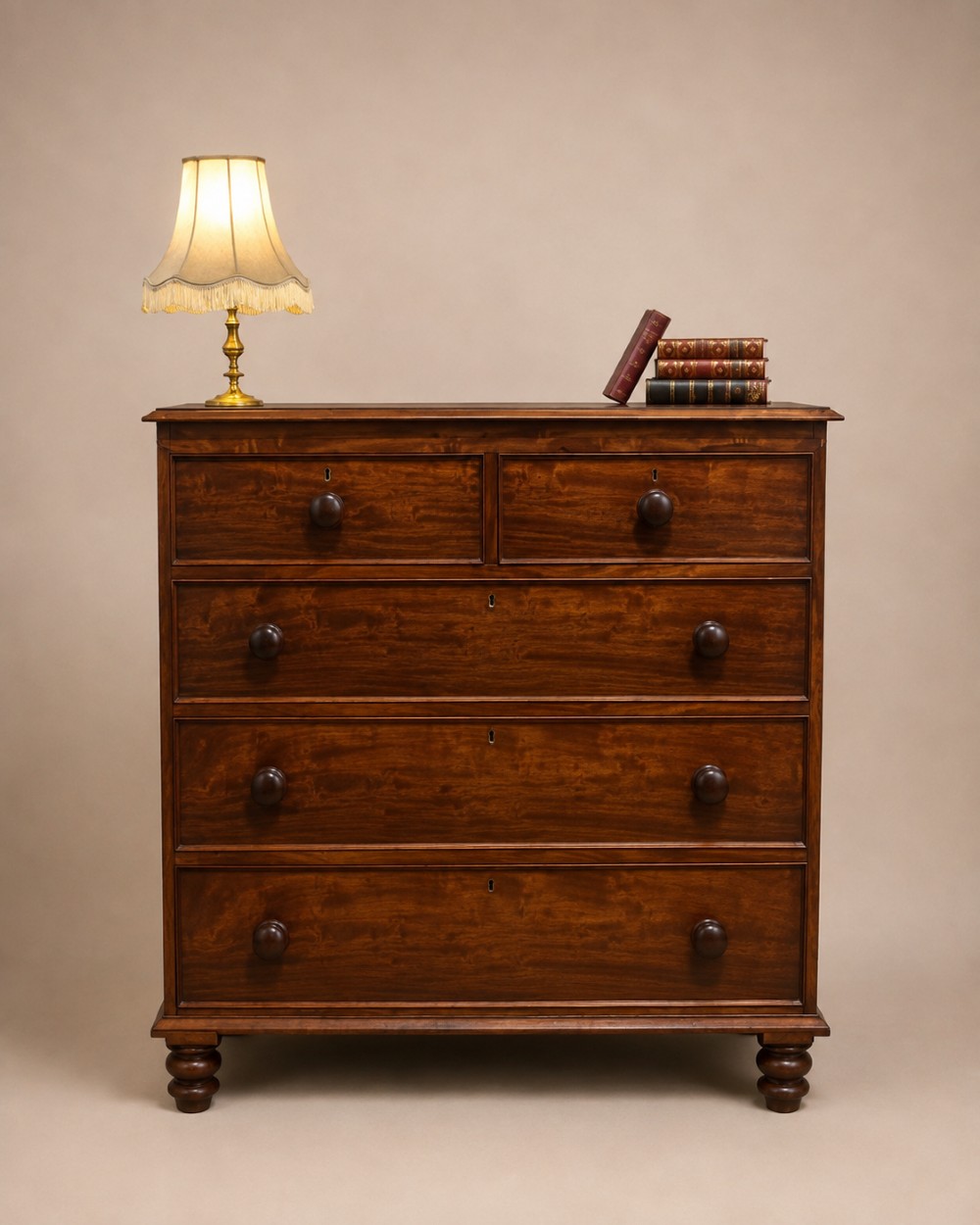 A 19th-century mahogany chest of drawers with a two-over-three drawer configuration, turned wooden knobs, and turned bun feet.