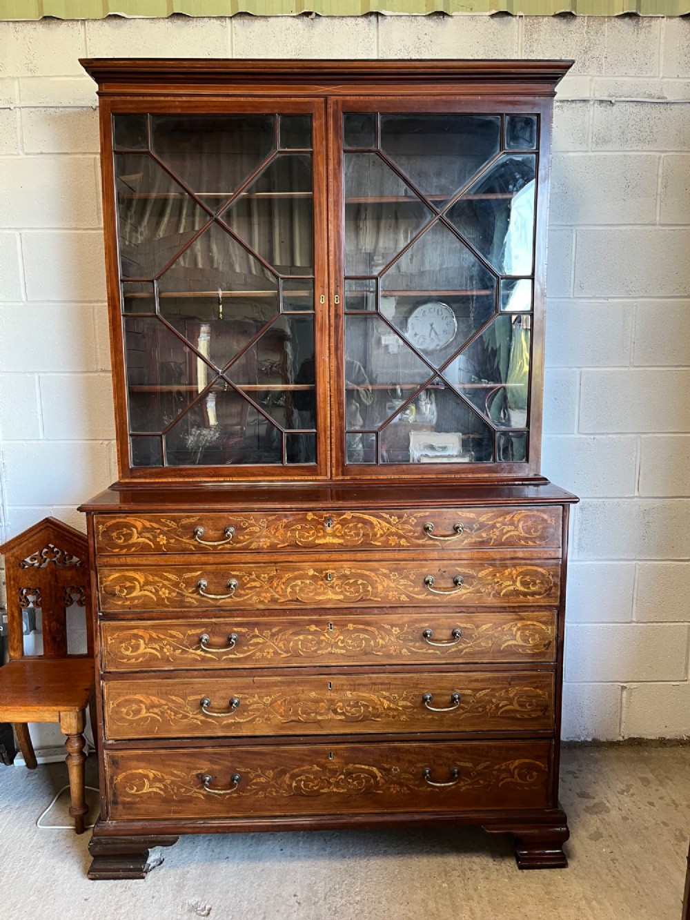 A 19th-century mahogany secretaire bookcase featuring an upper cabinet with geometric astragal glazed doors above a chest of drawers embellished with floral marquetry inlay. View IX