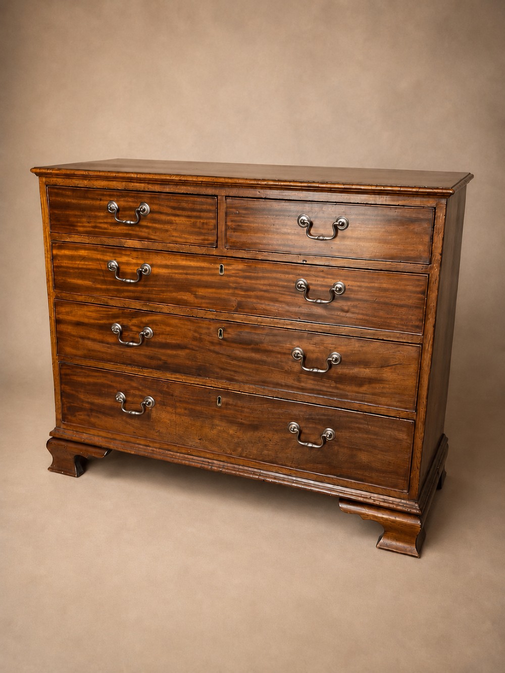 A Georgian mahogany chest of drawers featuring two short over three long graduated drawers with brass swan-neck handles and bracket feet. View II