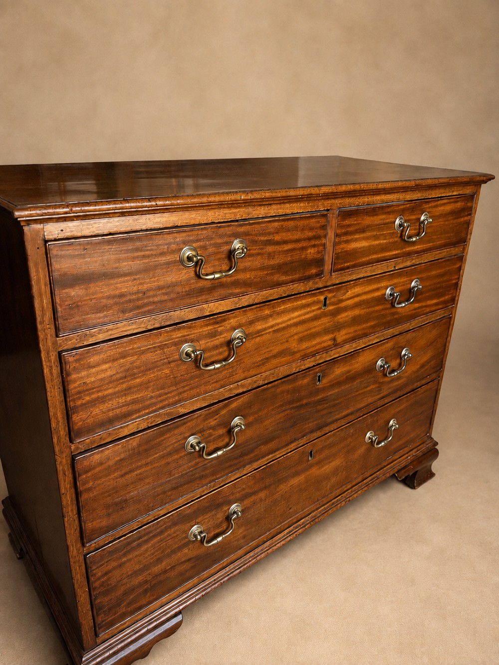 A Georgian mahogany chest of drawers featuring two short over three long graduated drawers with brass swan-neck handles and bracket feet. View V