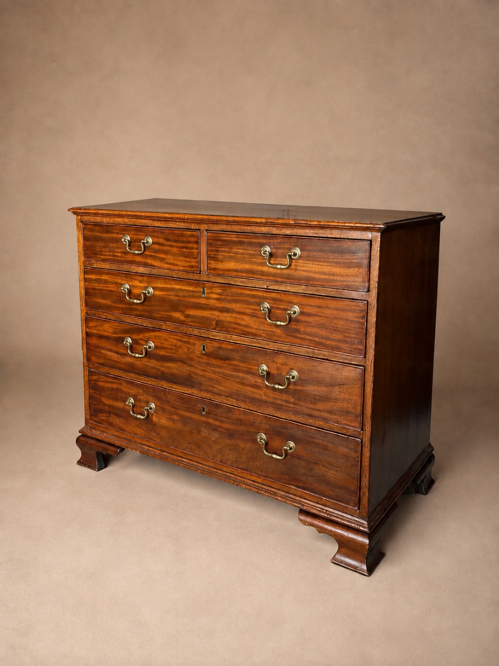 A Georgian mahogany chest of drawers featuring two short over three long graduated drawers with brass swan-neck handles and bracket feet. View VI