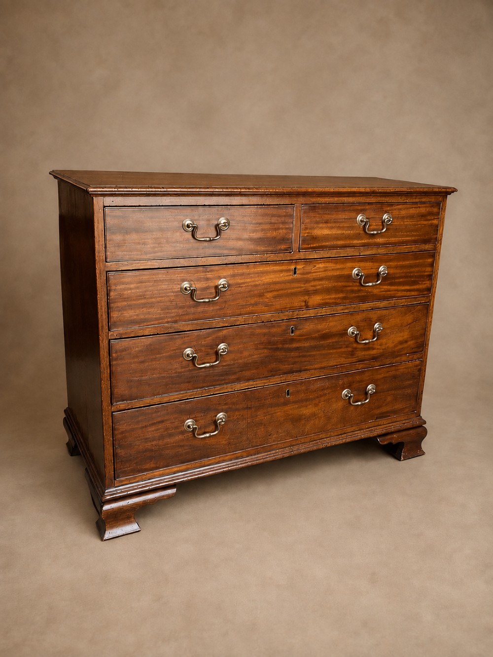A Georgian mahogany chest of drawers featuring two short over three long graduated drawers with brass swan-neck handles and bracket feet. View VII