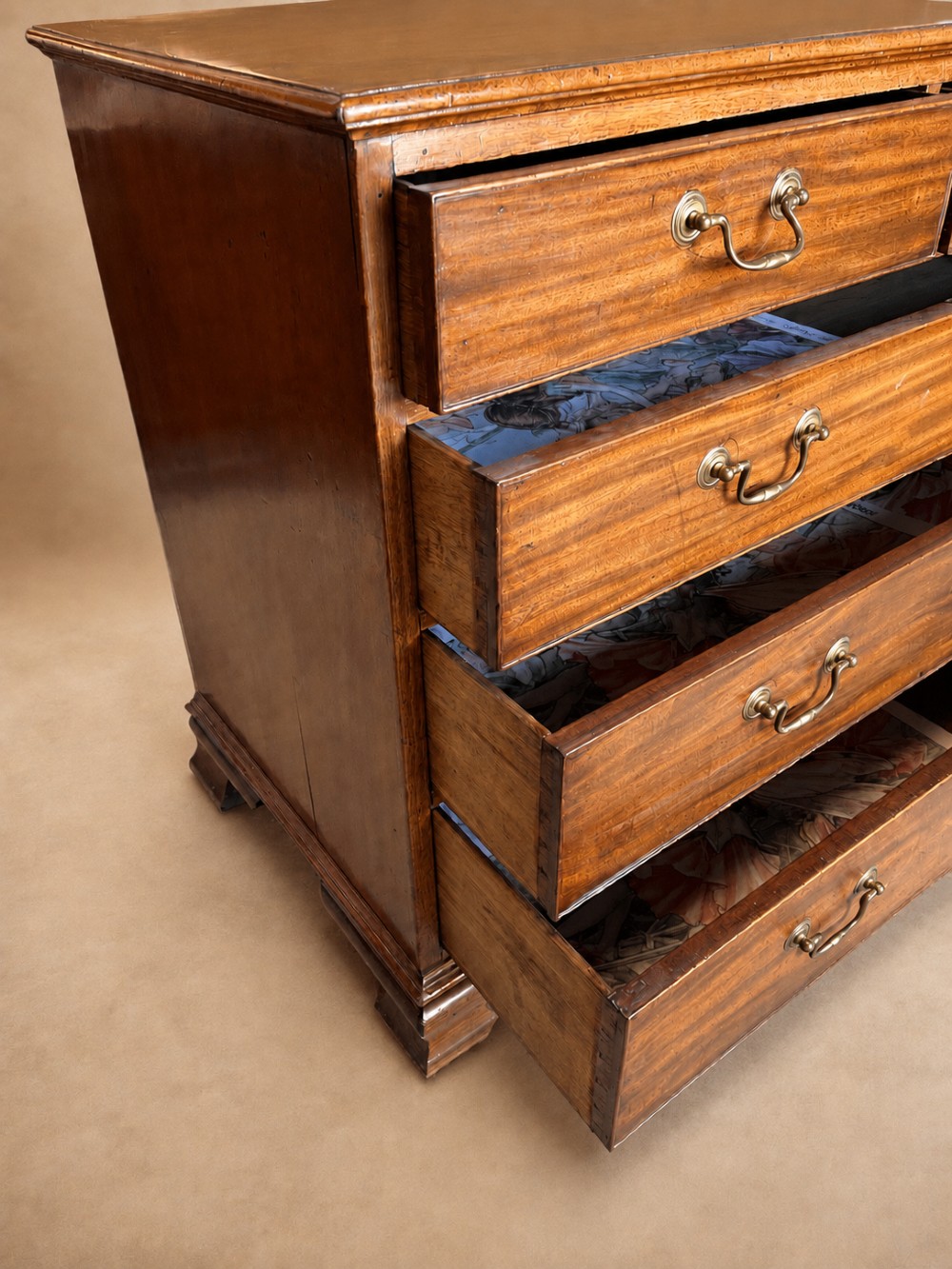 A Georgian mahogany chest of drawers featuring two short over three long graduated drawers with brass swan-neck handles and bracket feet. View IX