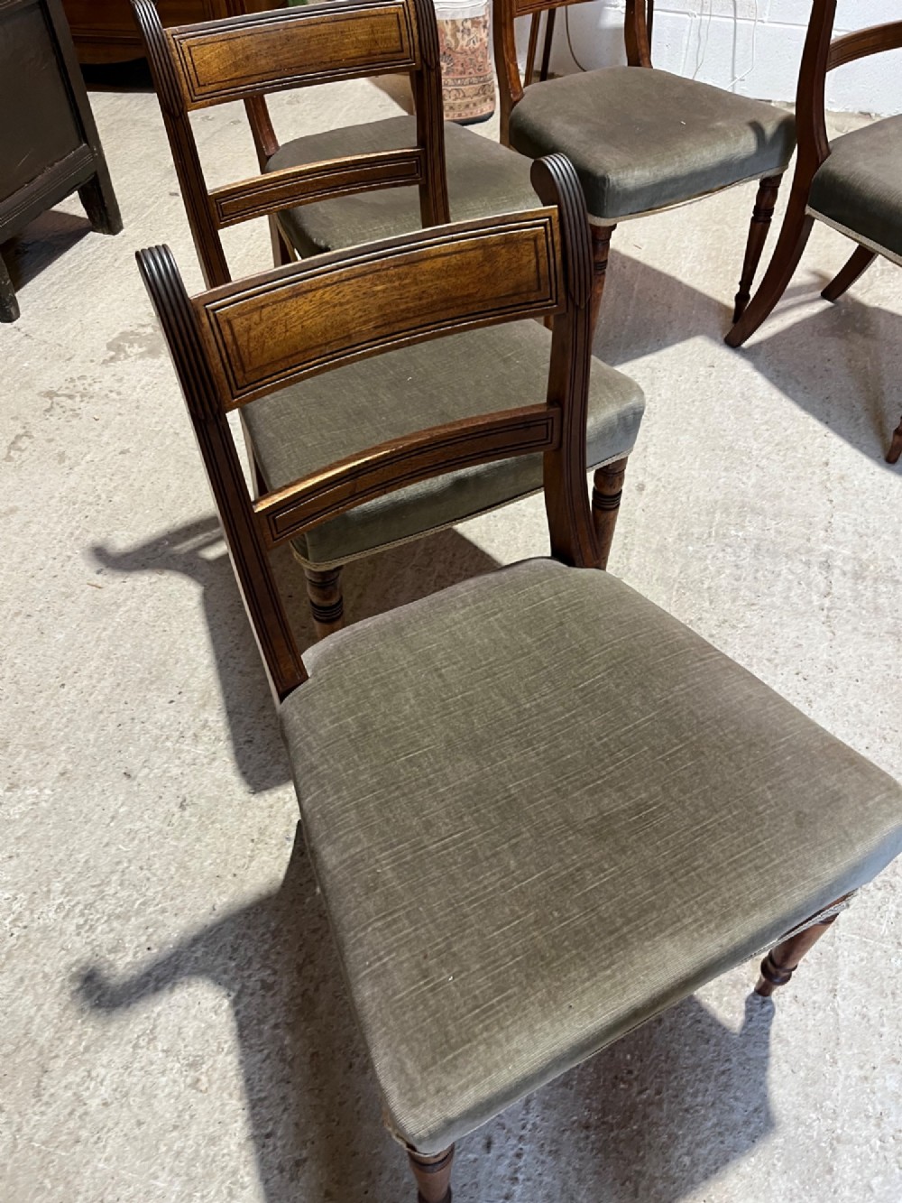 Set of six Regency mahogany dining chairs featuring horizontal bar backrests, green velvet seats, turned front legs, and splayed rear legs. View V