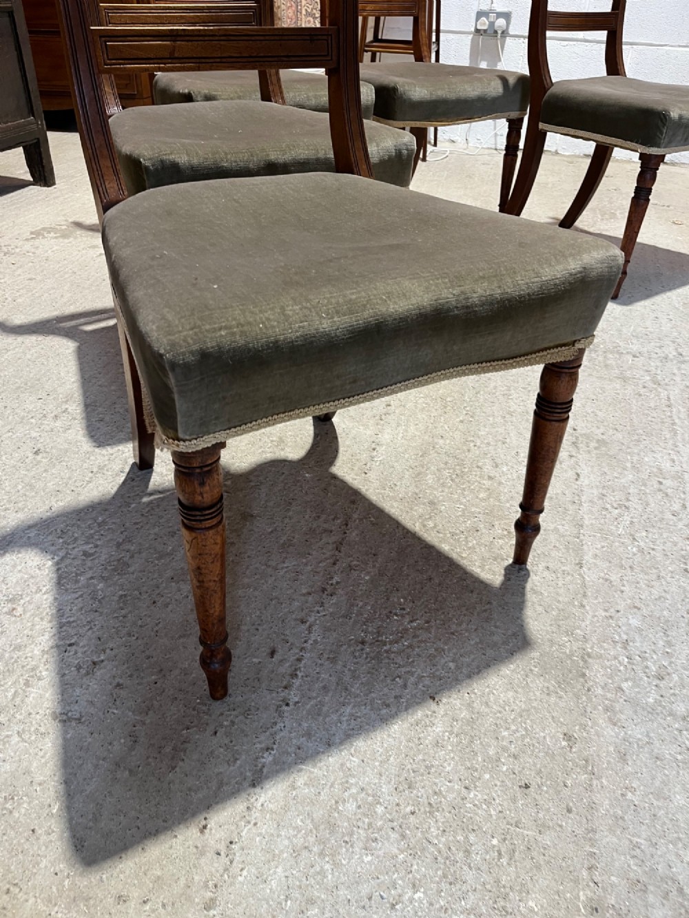 Set of six Regency mahogany dining chairs featuring horizontal bar backrests, green velvet seats, turned front legs, and splayed rear legs. View VI
