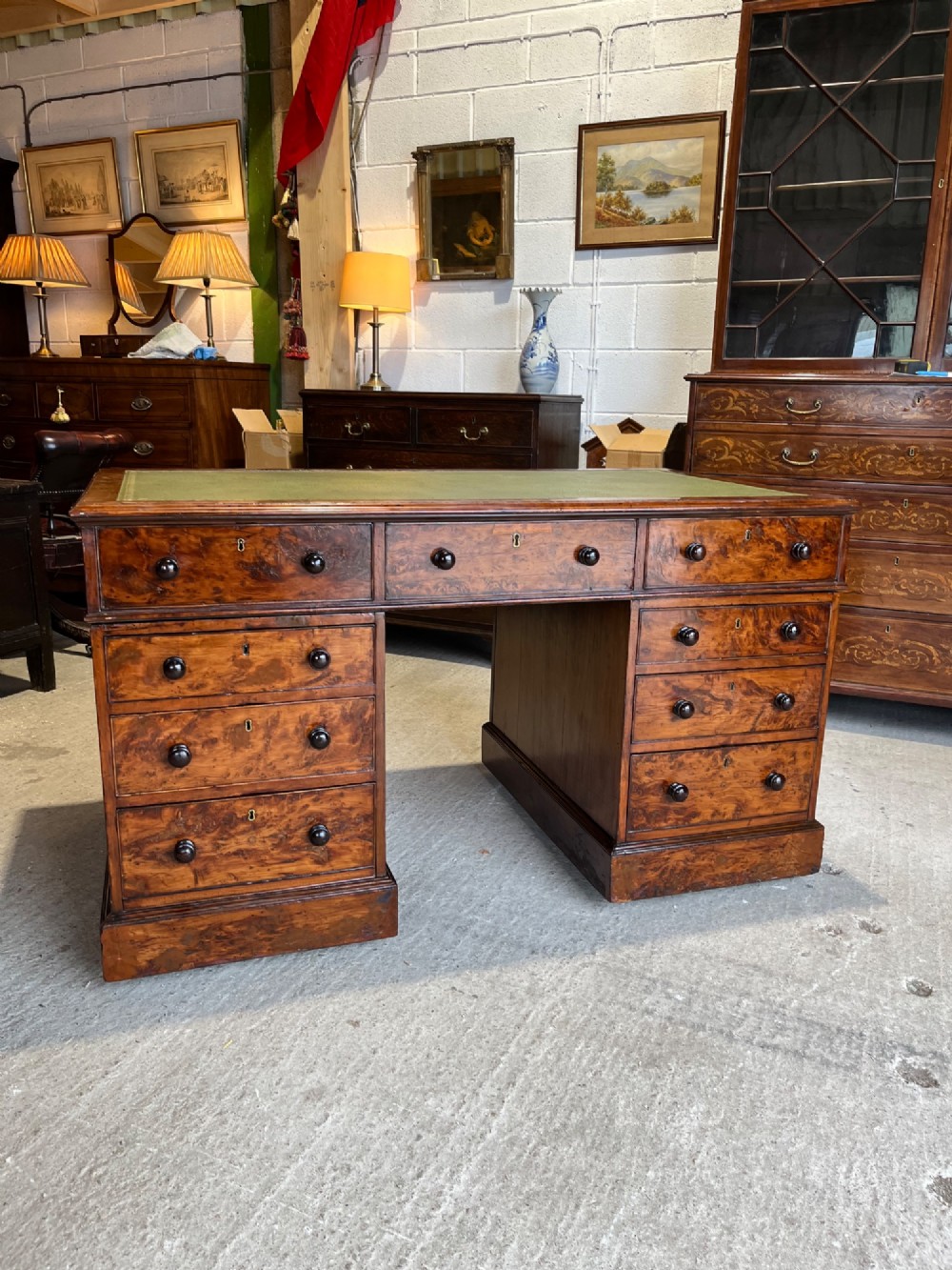A nineteenth-century Victorian burr walnut pedestal desk featuring a green leather writing surface, multiple drawers with turned wooden handles, and a plinth base. View II