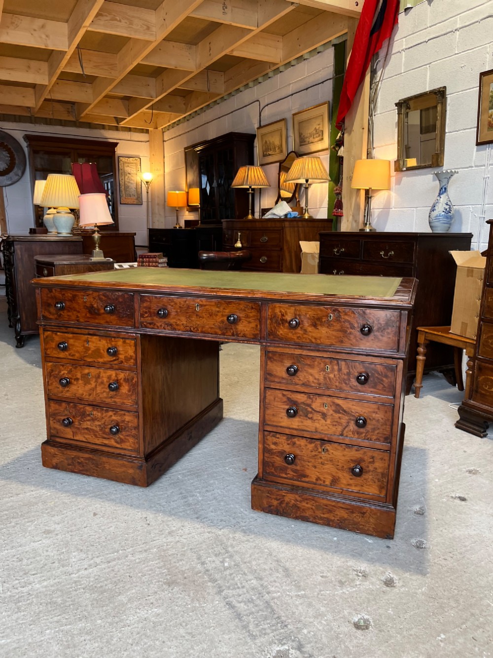 A nineteenth-century Victorian burr walnut pedestal desk featuring a green leather writing surface, multiple drawers with turned wooden handles, and a plinth base. View III