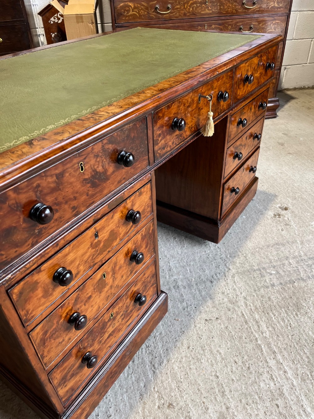 A nineteenth-century Victorian burr walnut pedestal desk featuring a green leather writing surface, multiple drawers with turned wooden handles, and a plinth base. View XII