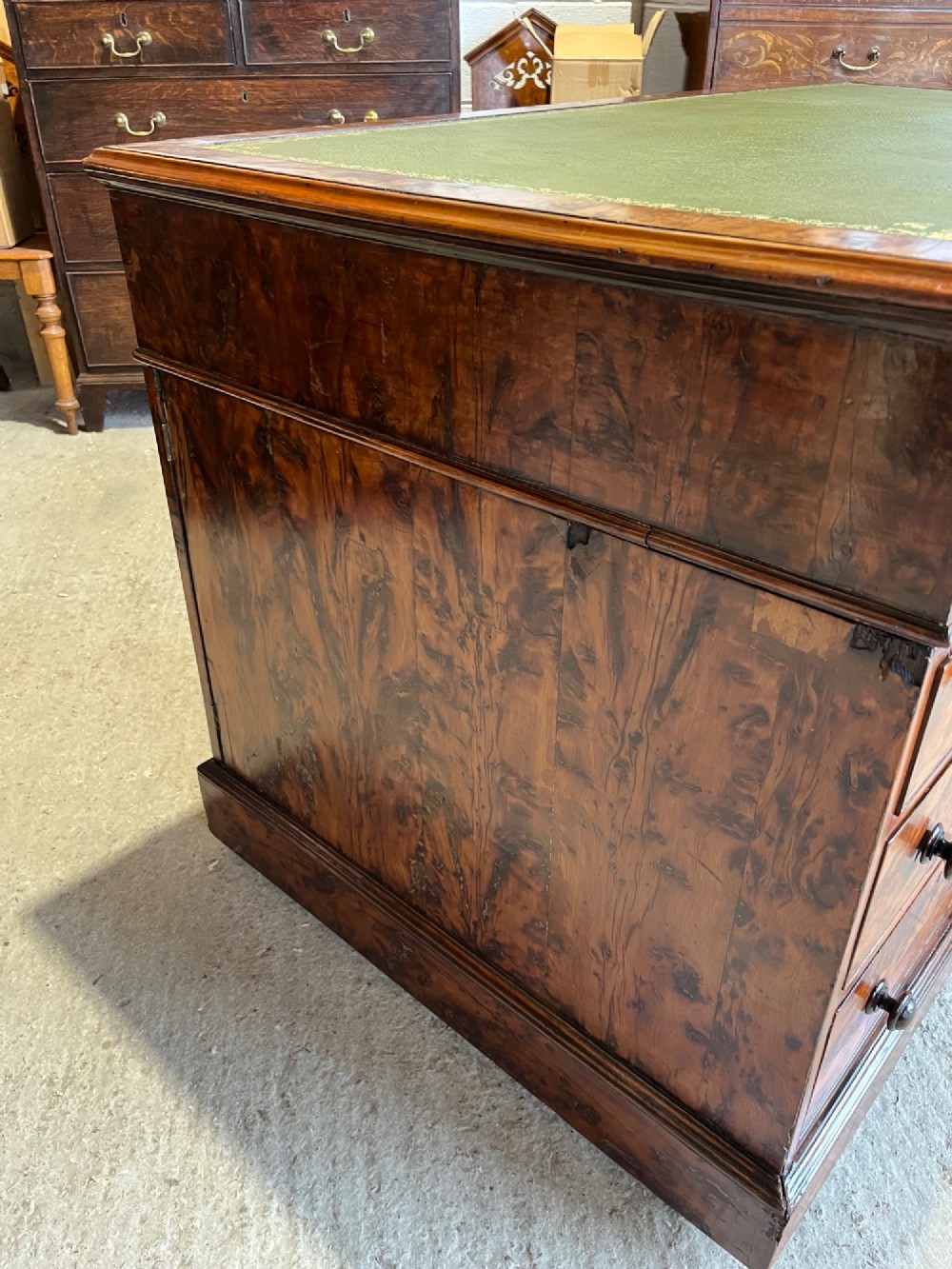 A nineteenth-century Victorian burr walnut pedestal desk featuring a green leather writing surface, multiple drawers with turned wooden handles, and a plinth base. View XIII