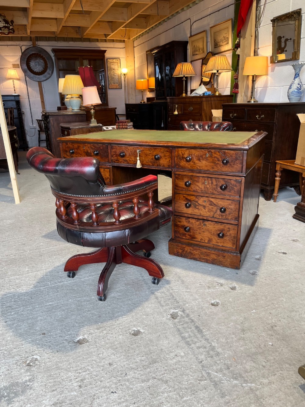 A nineteenth-century Victorian burr walnut pedestal desk featuring a green leather writing surface, multiple drawers with turned wooden handles, and a plinth base. View XIV