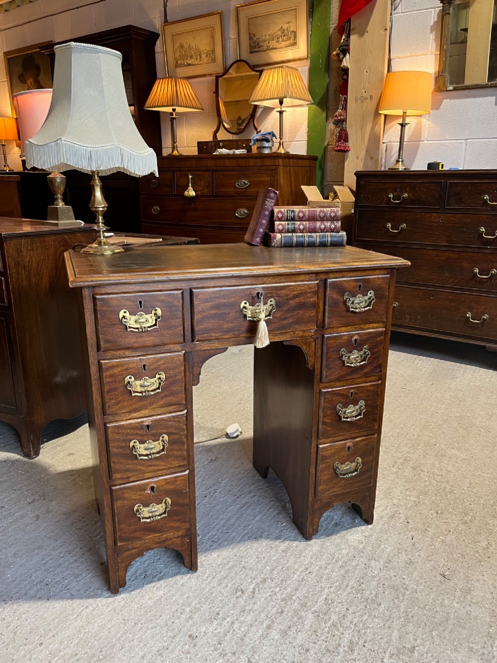 A late 19th-century dark mahogany kneehole desk featuring nine drawers with decorative brass handles and a central kneehole recess. View II