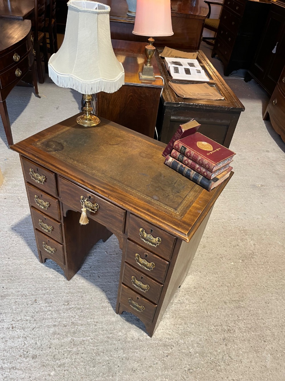 A late 19th-century dark mahogany kneehole desk featuring nine drawers with decorative brass handles and a central kneehole recess. View V