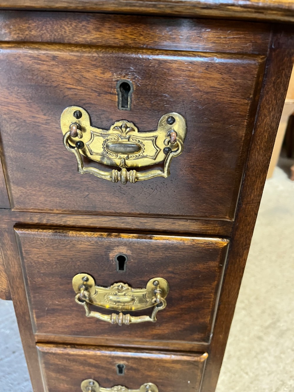 A late 19th-century dark mahogany kneehole desk featuring nine drawers with decorative brass handles and a central kneehole recess. View IX