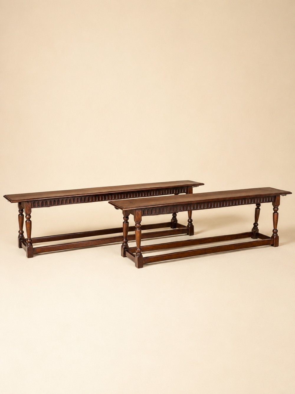 A pair of long dark oak benches featuring hand-carved friezes, turned baluster legs, and sturdy floor-level stretchers. View II