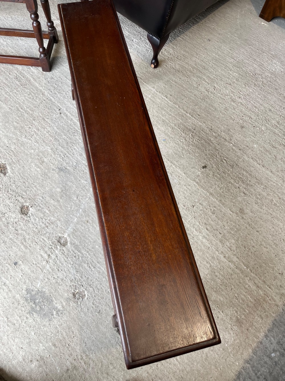 A pair of long dark oak benches featuring hand-carved friezes, turned baluster legs, and sturdy floor-level stretchers. View V