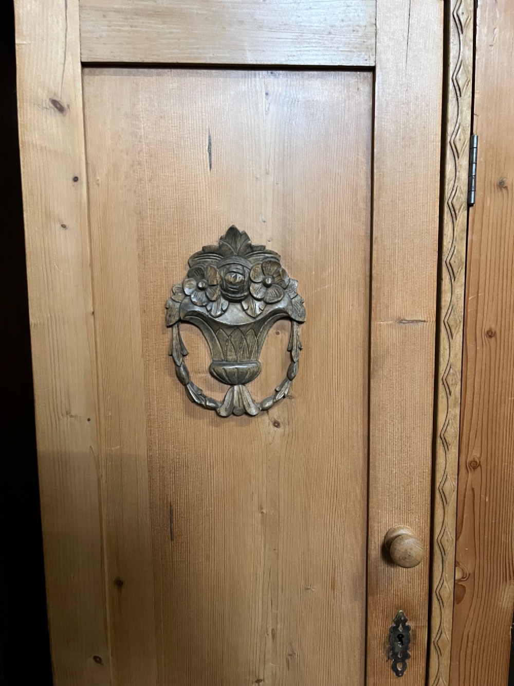 A 19th-century pine triple wardrobe featuring a central arched mirrored door, carved relief motifs on the side panels, and turned feet. View II