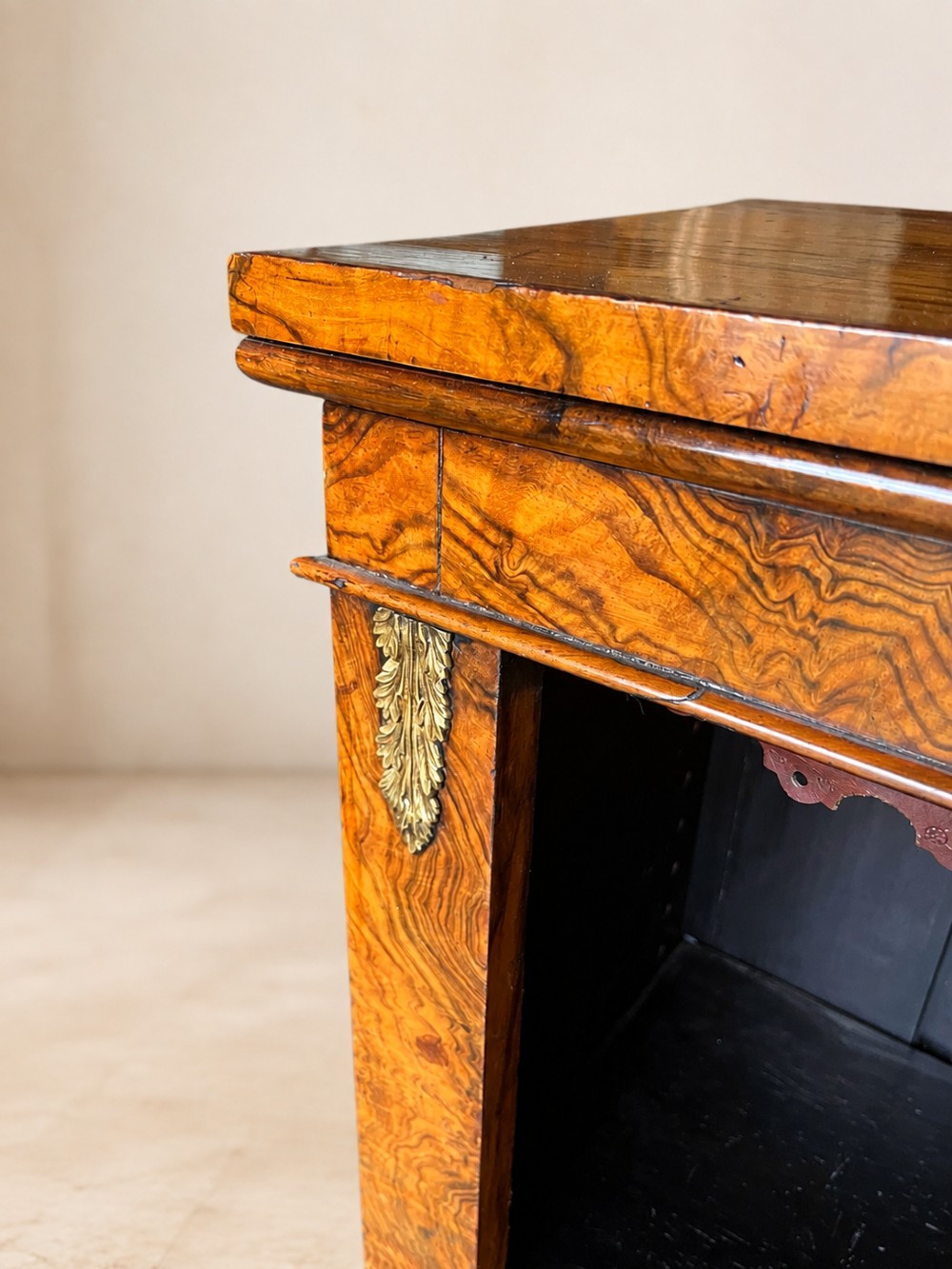 A 19th-century open walnut bookcase featuring highly figured veneer, brass corner mounts, three shelves with scalloped trim, and a dark painted back panel. View V