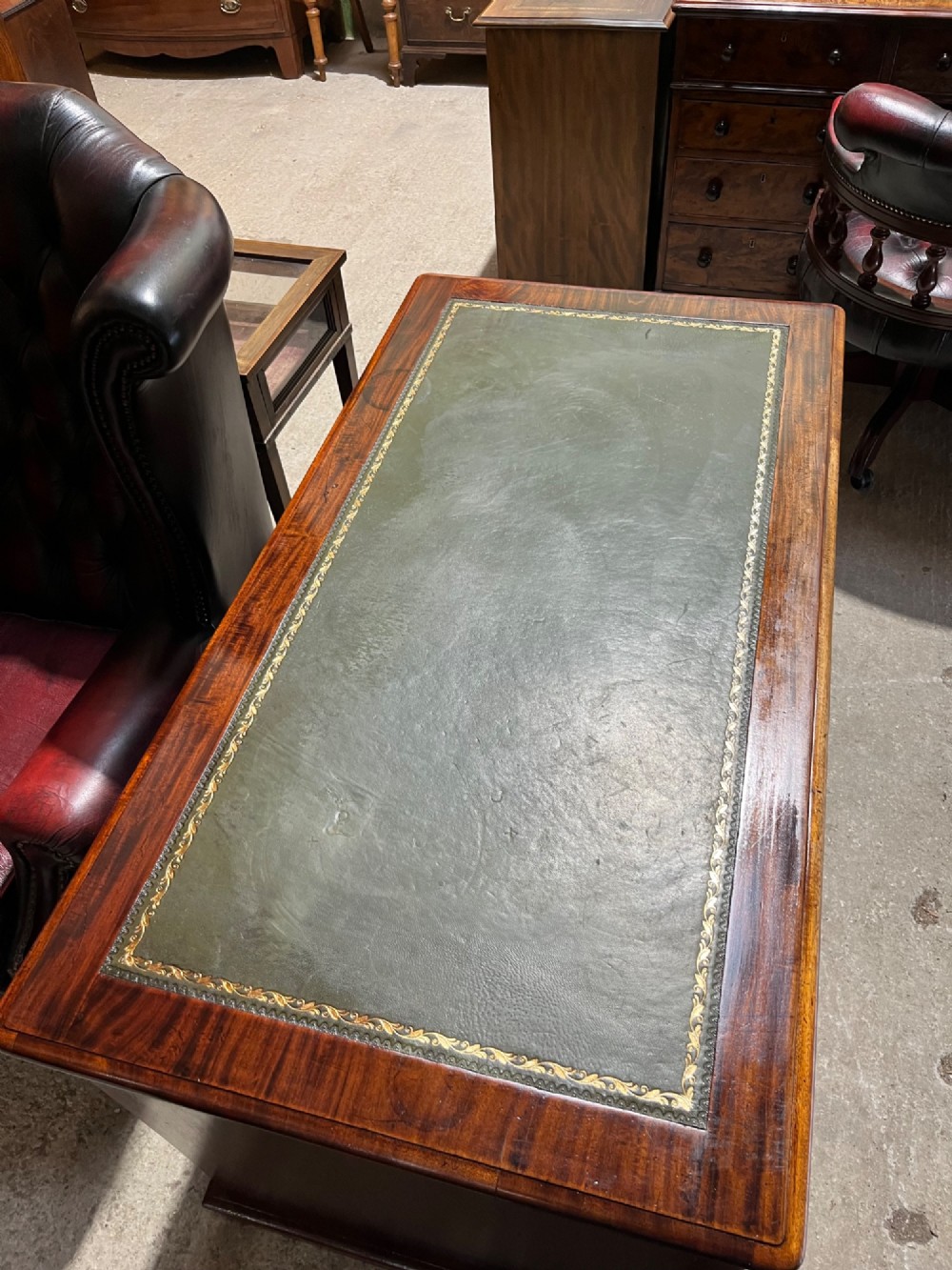 A 19th-century mahogany pedestal desk featuring an inset green leather top, brass ring pull handles, and nine drawers over plinth bases. View X