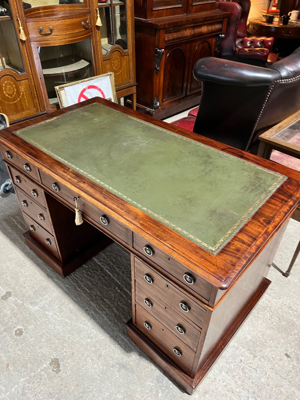 A 19th-century mahogany pedestal desk featuring an inset green leather top, brass ring pull handles, and nine drawers over plinth bases. View XI