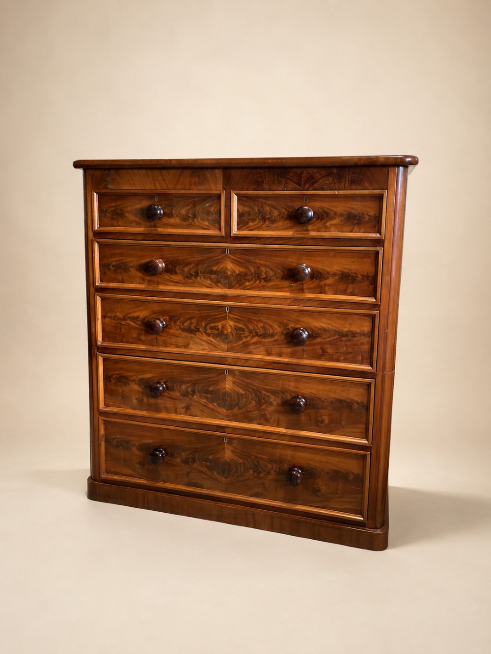 A tall nineteenth-century mahogany chest of drawers featuring two short top drawers above four long drawers with turned wooden handles on a solid plinth base.