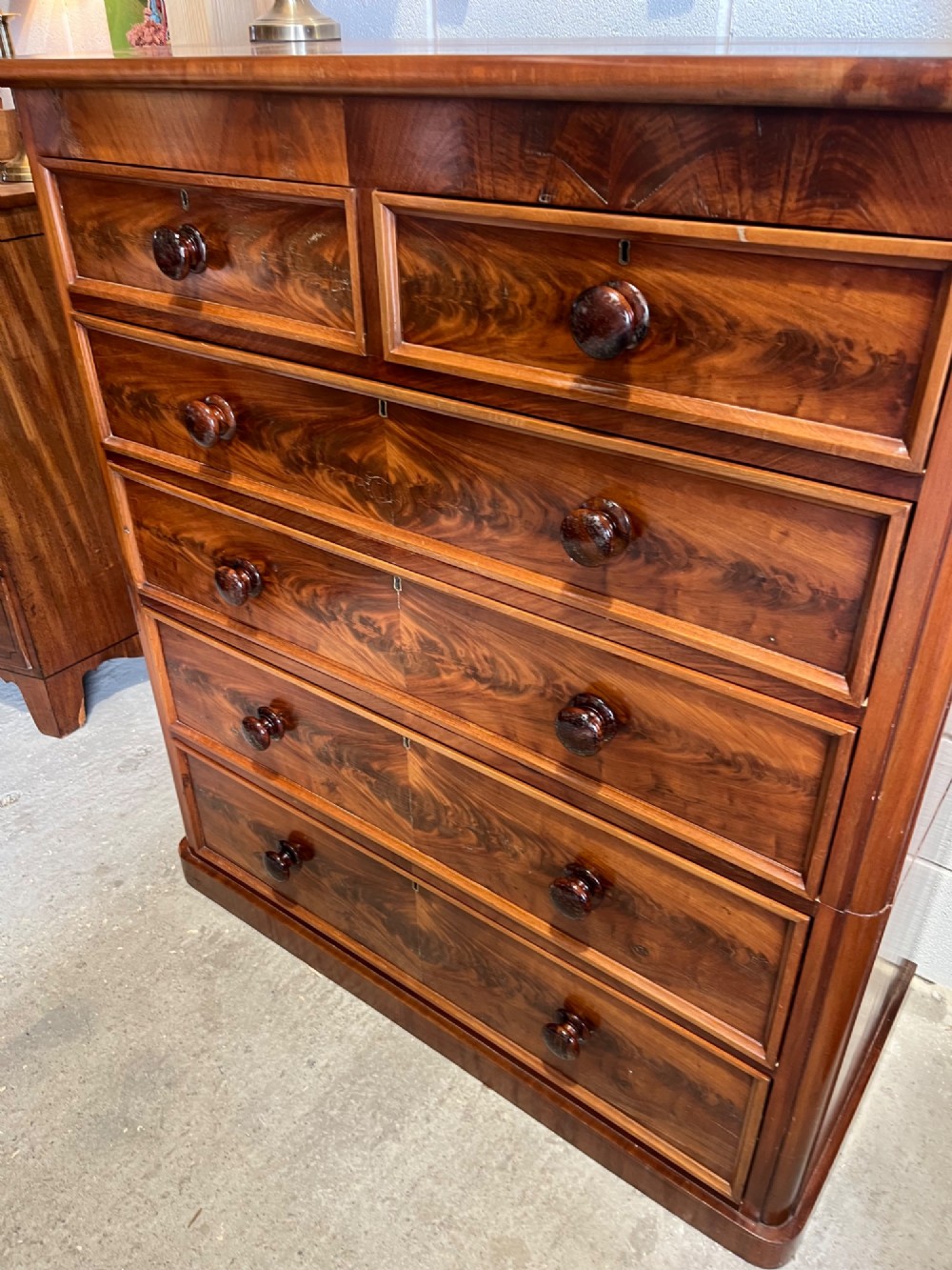 A tall nineteenth-century mahogany chest of drawers featuring two short top drawers above four long drawers with turned wooden handles on a solid plinth base. View V