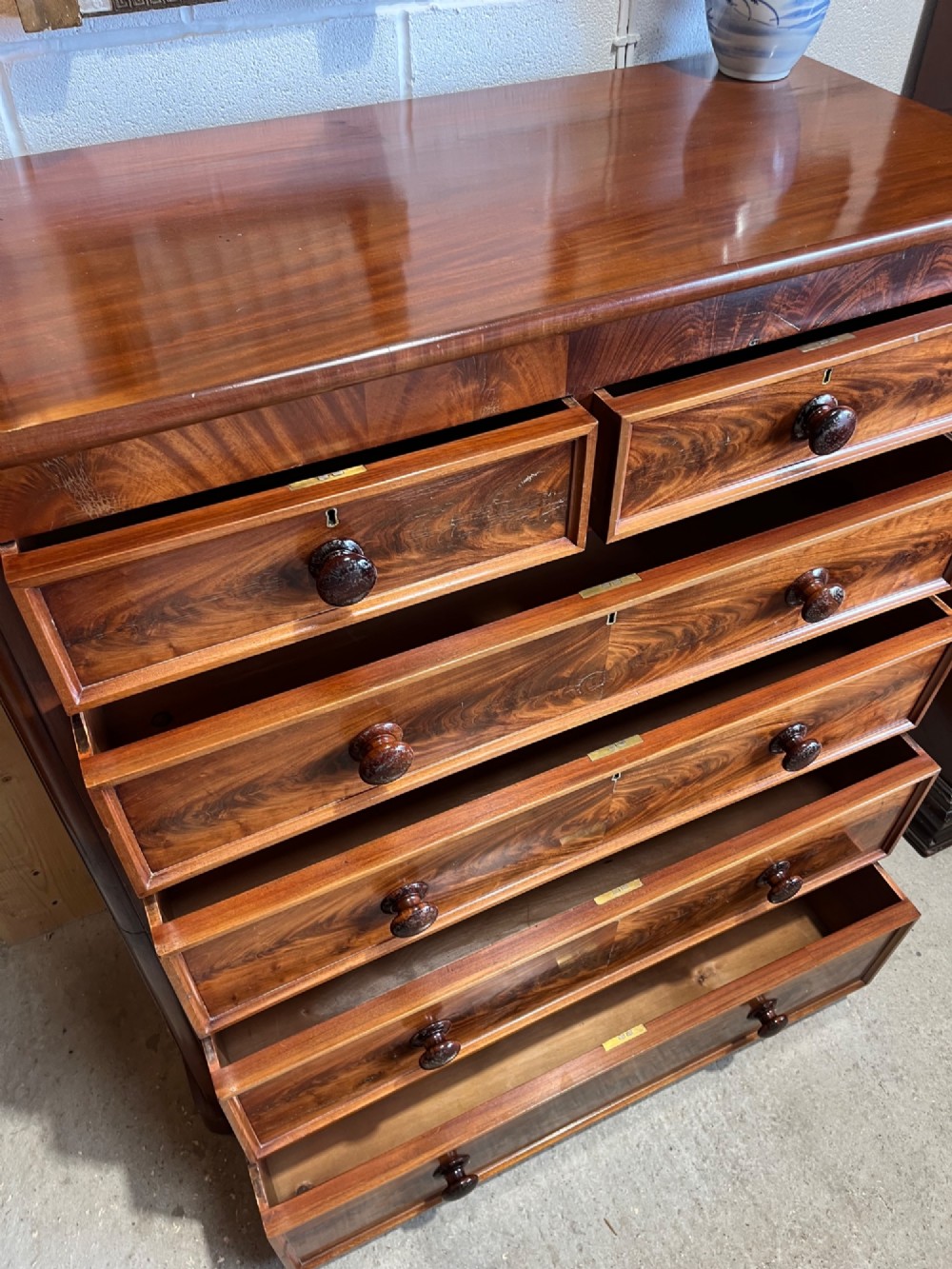A tall nineteenth-century mahogany chest of drawers featuring two short top drawers above four long drawers with turned wooden handles on a solid plinth base. View IX