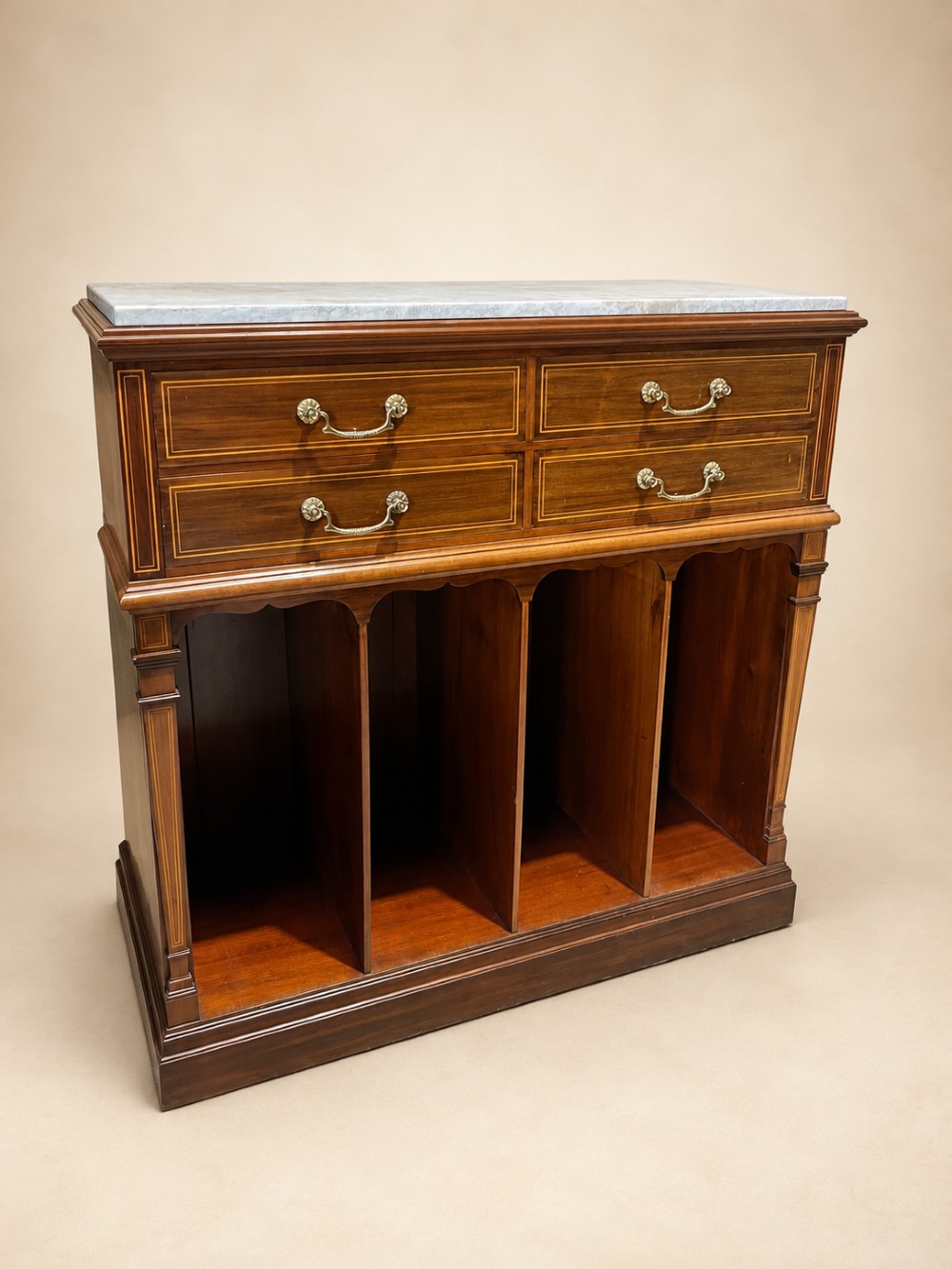 A late 19th-century inlaid mahogany cabinet featuring a grey marble surface, four drawers with string inlay and brass drop handles, above four vertical open storage divisions.