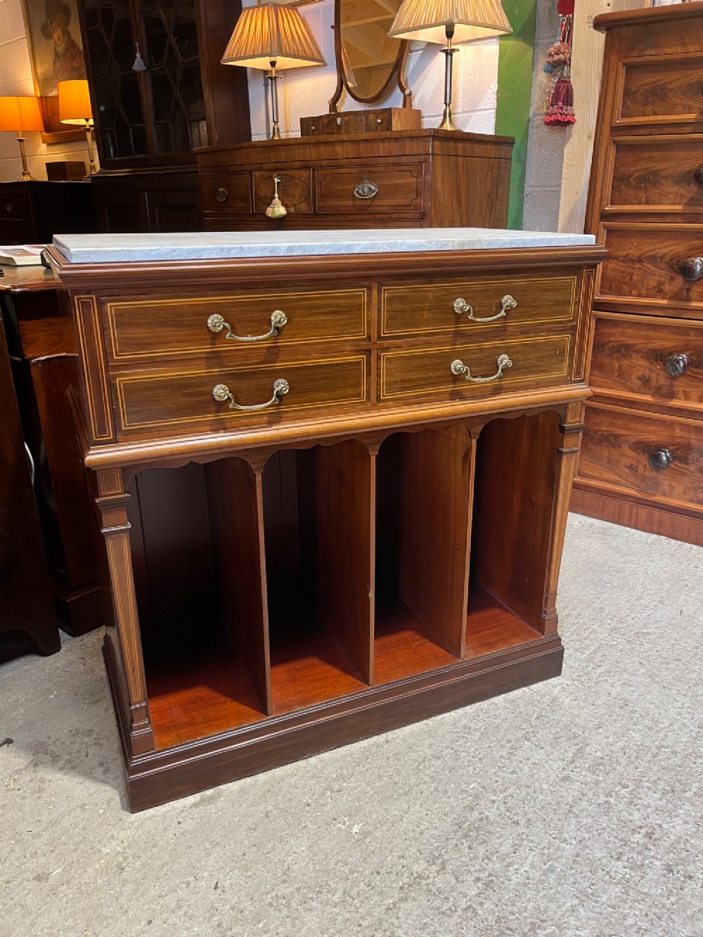 A late 19th-century inlaid mahogany cabinet featuring a grey marble surface, four drawers with string inlay and brass drop handles, above four vertical open storage divisions. View II