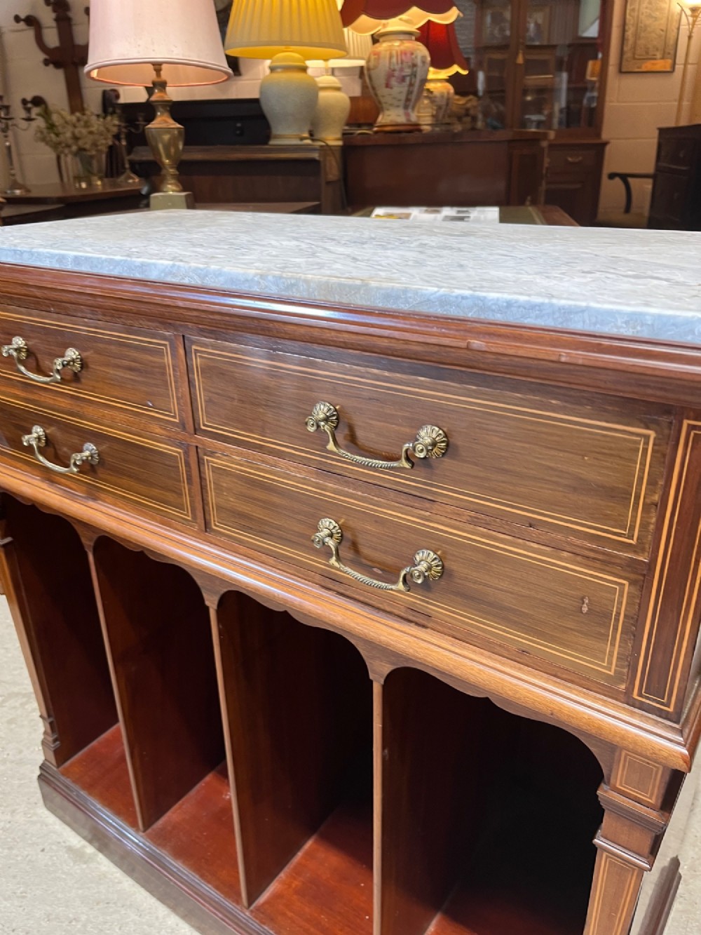 A late 19th-century inlaid mahogany cabinet featuring a grey marble surface, four drawers with string inlay and brass drop handles, above four vertical open storage divisions. View VI