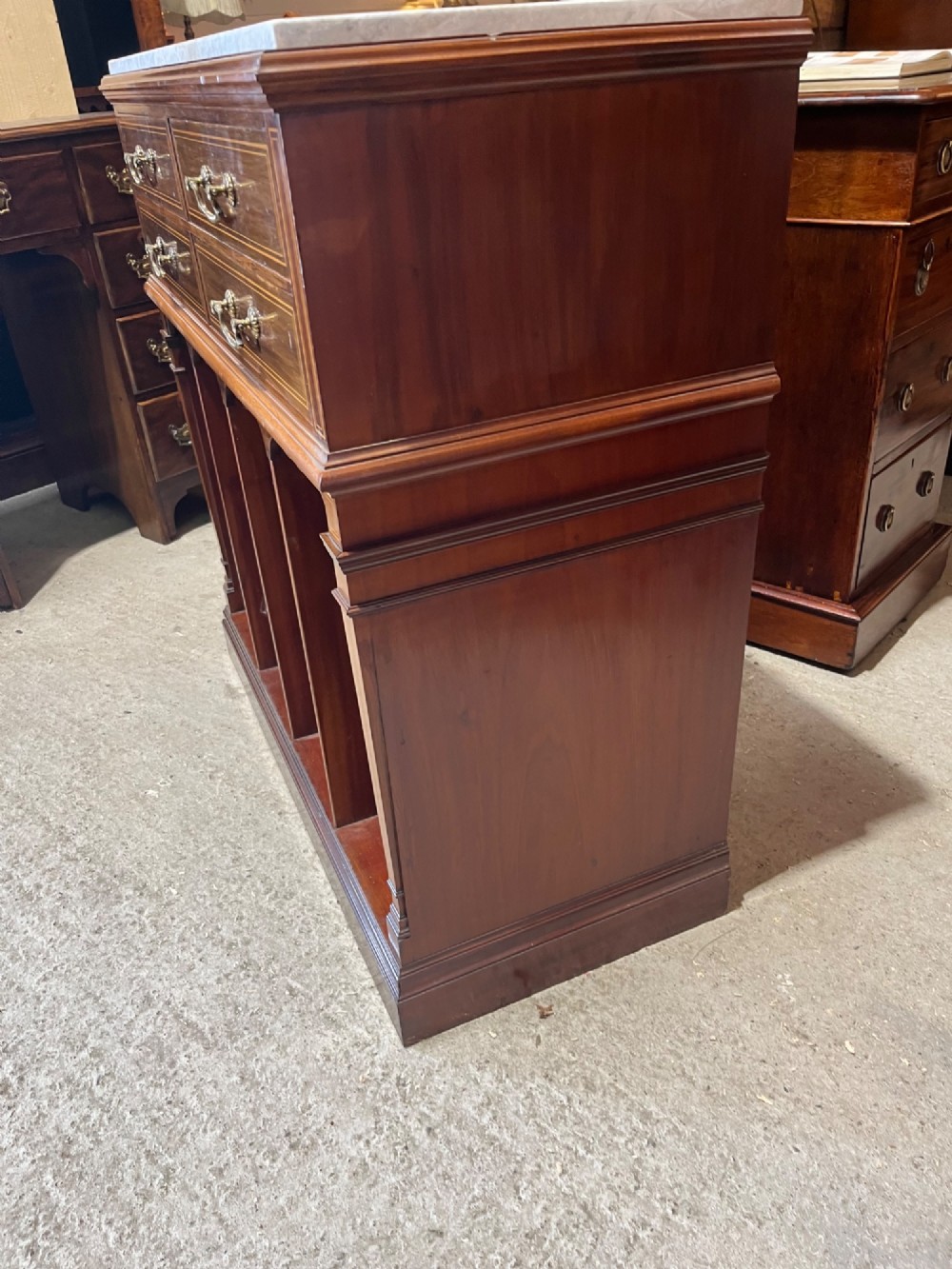 A late 19th-century inlaid mahogany cabinet featuring a grey marble surface, four drawers with string inlay and brass drop handles, above four vertical open storage divisions. View X