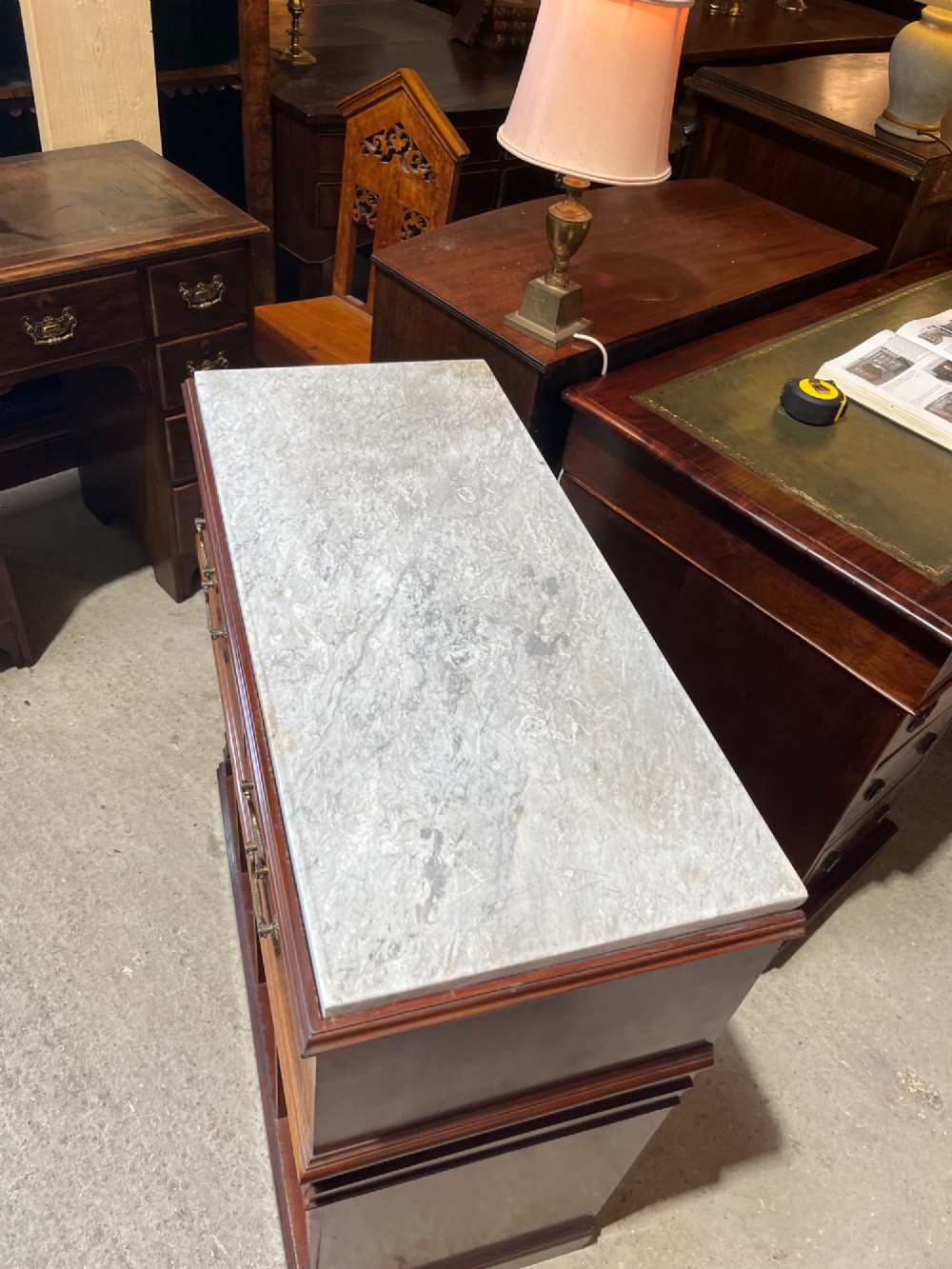 A late 19th-century inlaid mahogany cabinet featuring a grey marble surface, four drawers with string inlay and brass drop handles, above four vertical open storage divisions. View XI