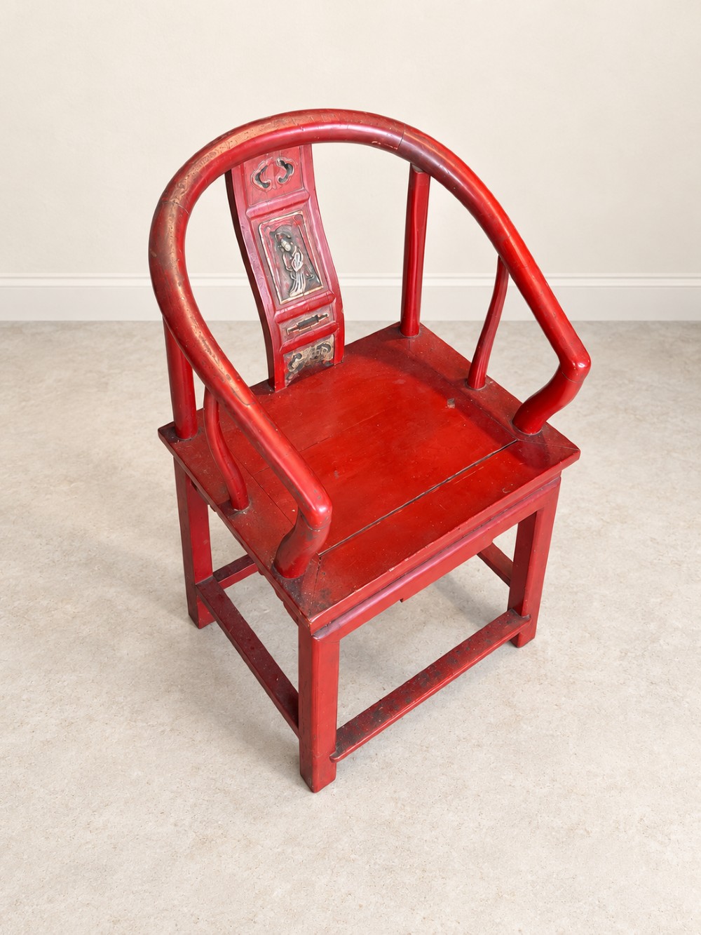 A traditional red lacquered Chinese armchair featuring a curved horseshoe backrest and a carved central splat. View II