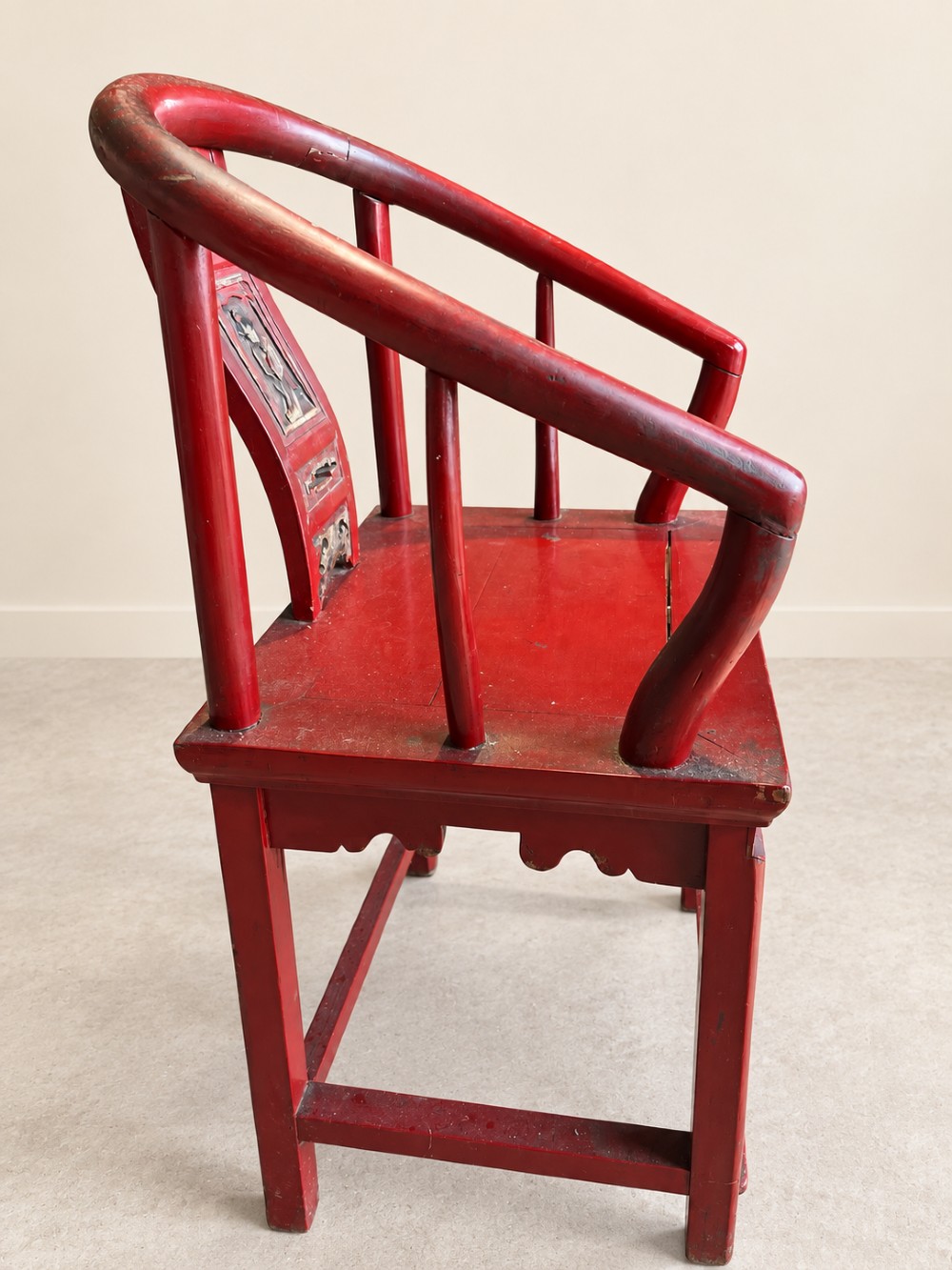 A traditional red lacquered Chinese armchair featuring a curved horseshoe backrest and a carved central splat. View VI