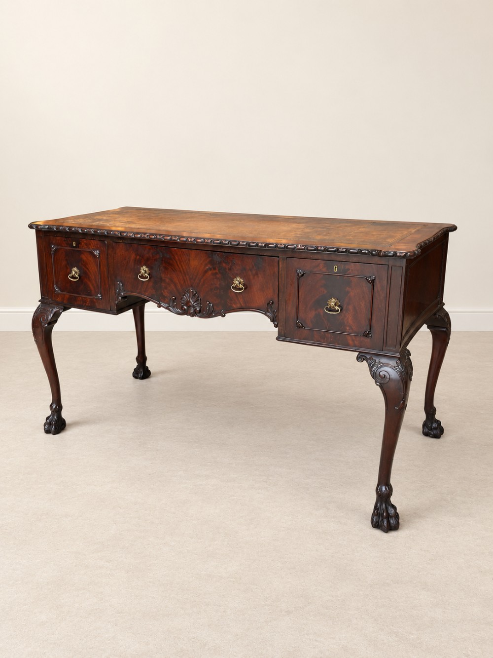 A dark mahogany writing table featuring three drawers, a carved shell apron, and cabriole legs with ball-and-claw feet. View II