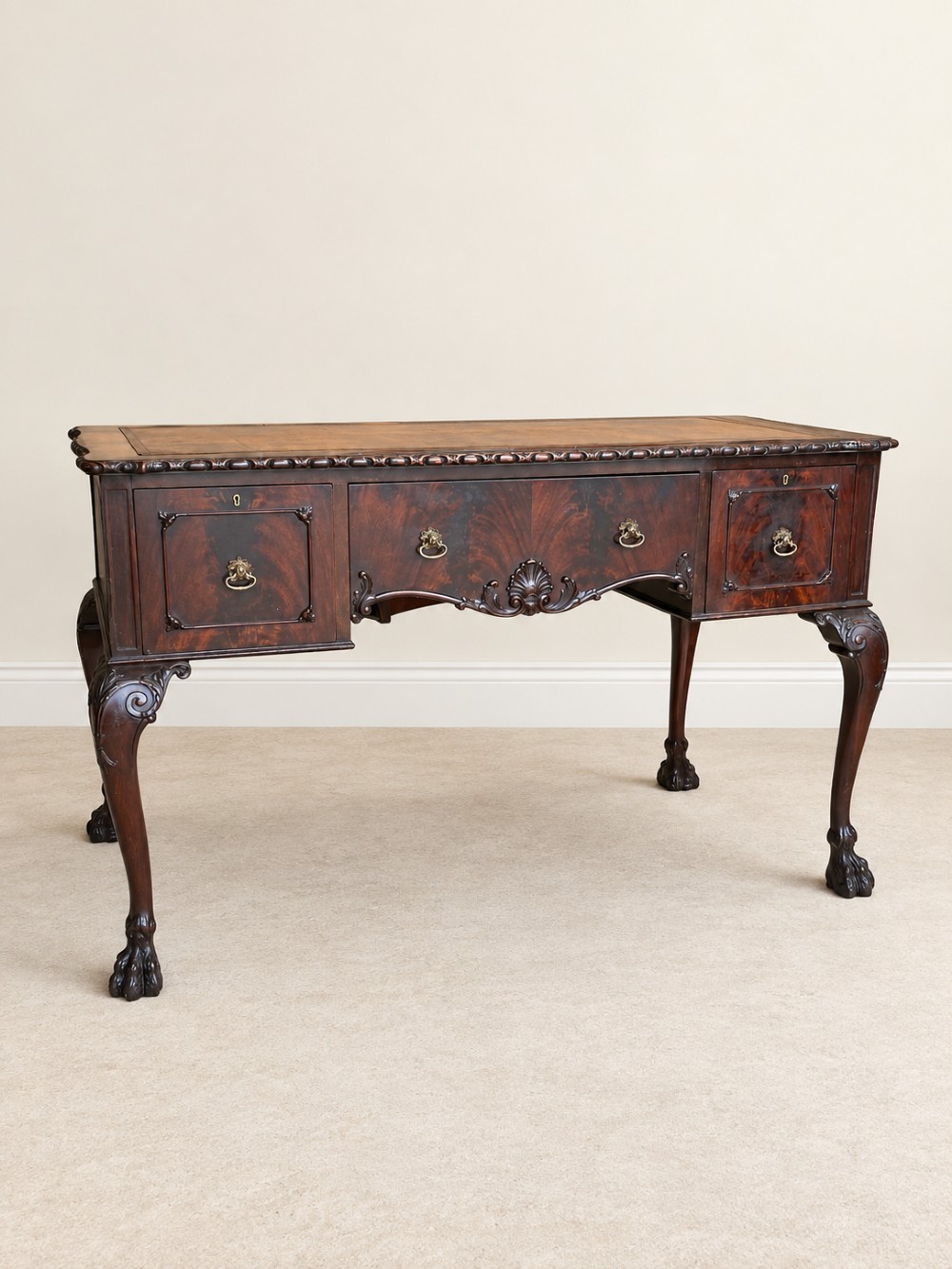 A dark mahogany writing table featuring three drawers, a carved shell apron, and cabriole legs with ball-and-claw feet. View III