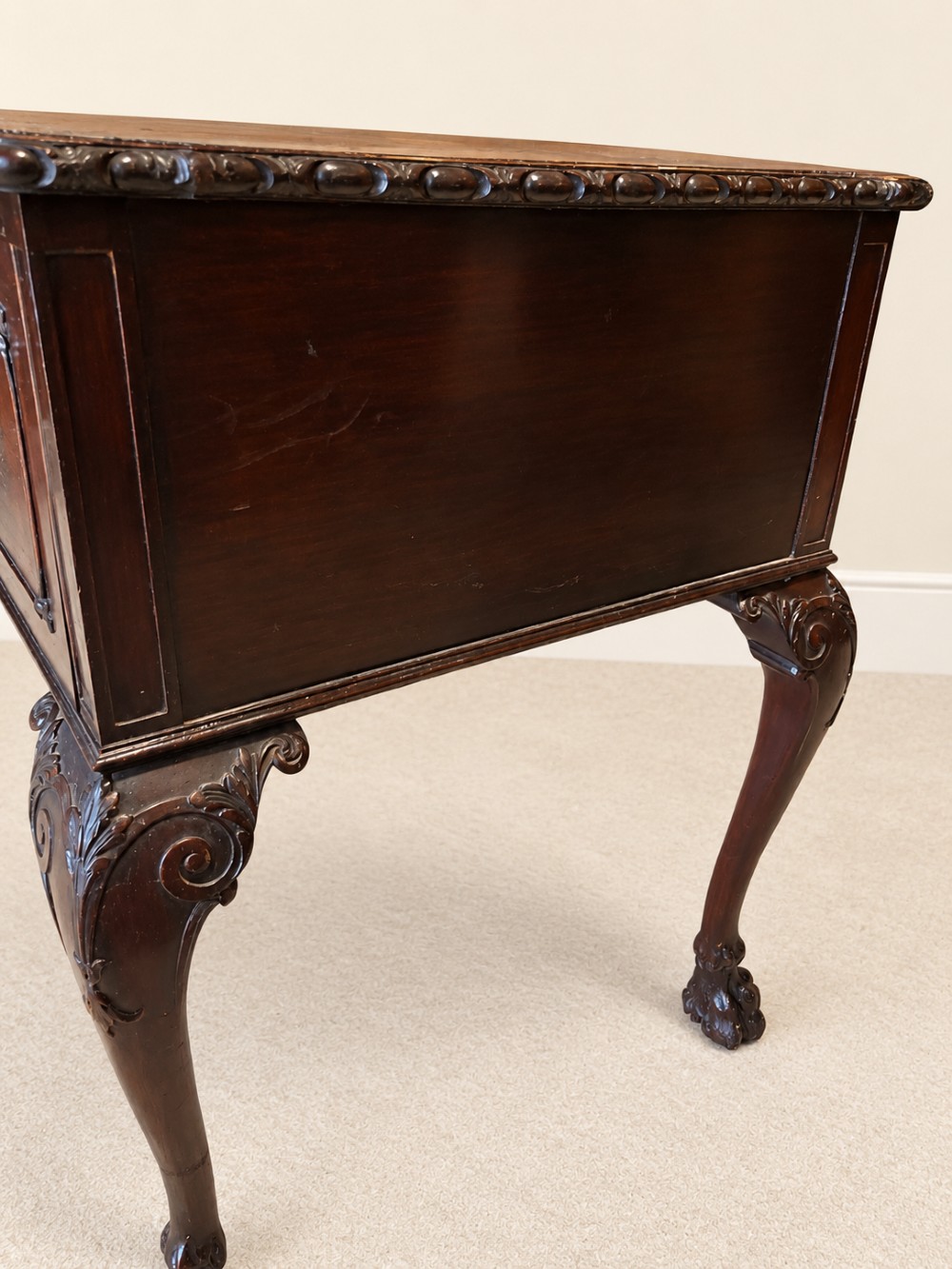 A dark mahogany writing table featuring three drawers, a carved shell apron, and cabriole legs with ball-and-claw feet. View VI