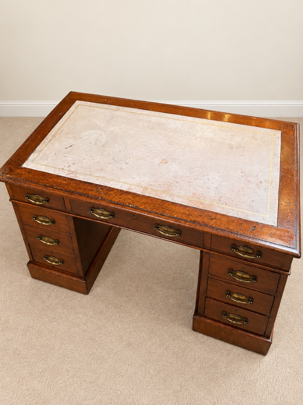 Late 19th-century oak pedestal desk featuring a tan leather-inset writing surface, nine drawers with brass handles, and solid plinth bases. View III