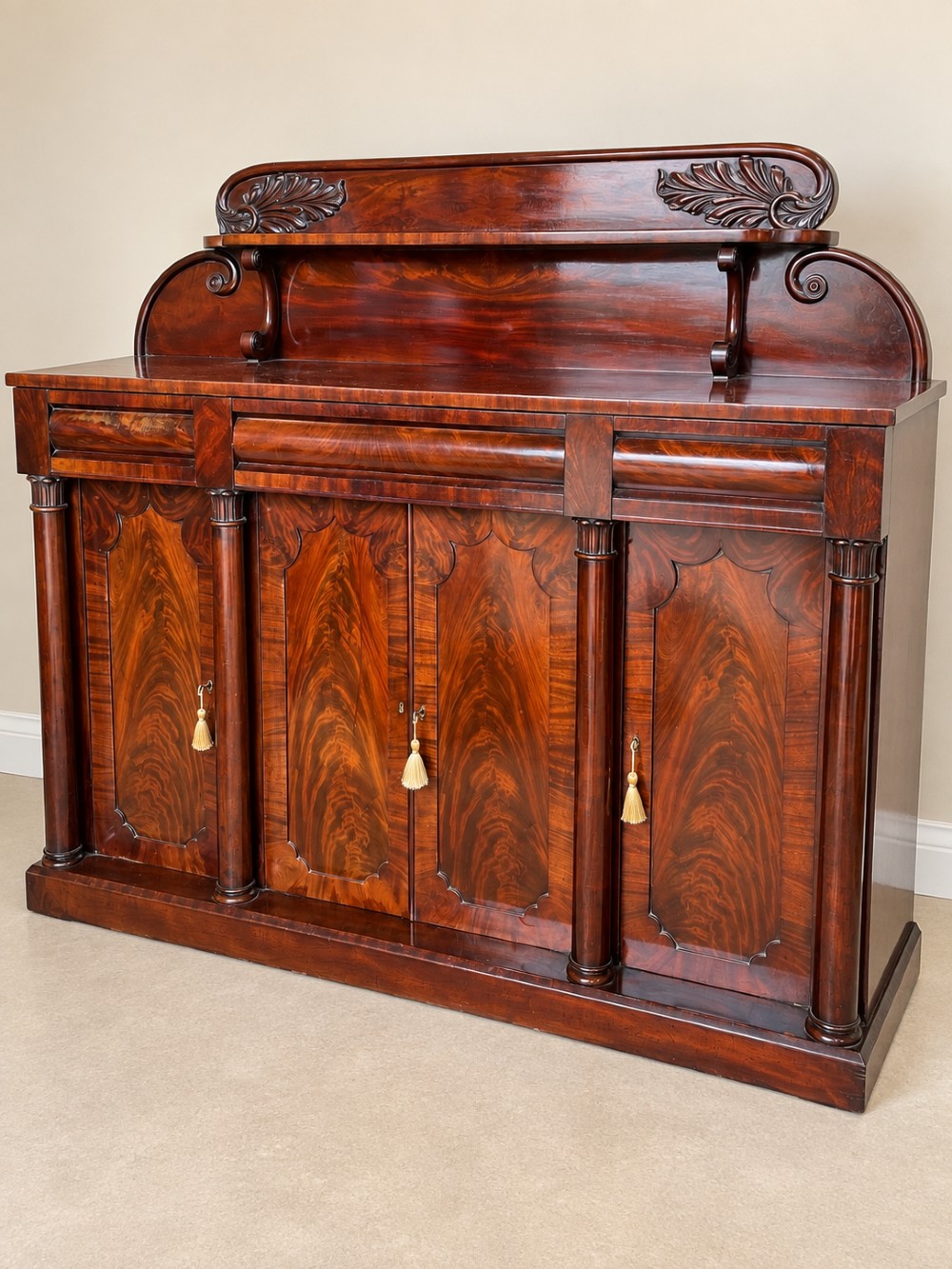 A 19th-century mahogany sideboard with a carved scrolled backboard, flame mahogany door panels, fluted columns, and a solid plinth base. View II