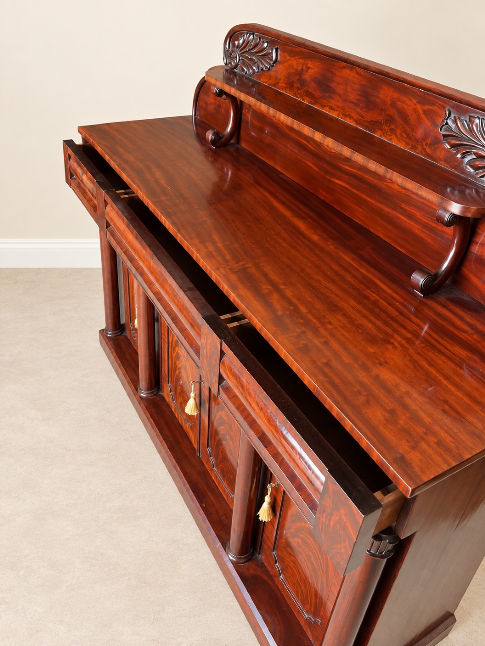 A 19th-century mahogany sideboard with a carved scrolled backboard, flame mahogany door panels, fluted columns, and a solid plinth base. View III